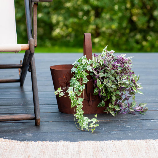 Rustic metal planter with handle, cut-out floral pattern, natural rusty finish
